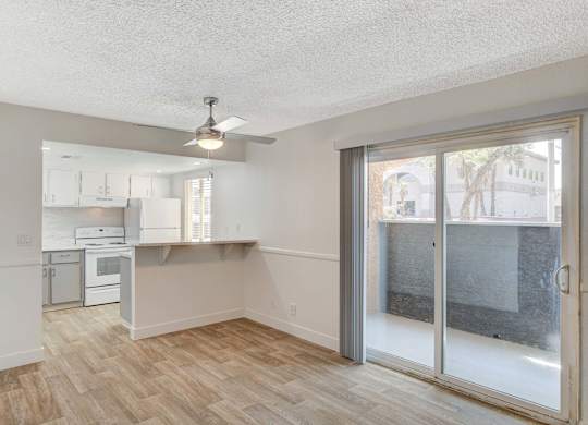 A room with a kitchen area and a sliding glass door.