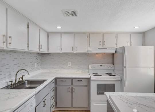 A kitchen with white cabinets and a marble countertop.