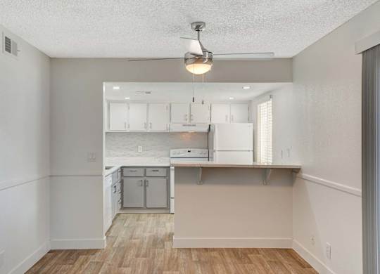 A kitchen with white cabinets and a wooden floor.