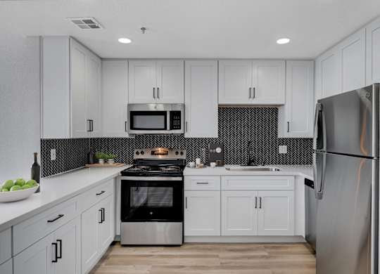 A modern kitchen with a stainless steel refrigerator, microwave, and oven.