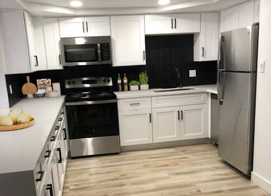A kitchen with white cabinets and a black backsplash.