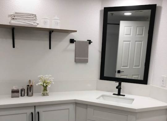 A white bathroom with a sink and a mirror.
