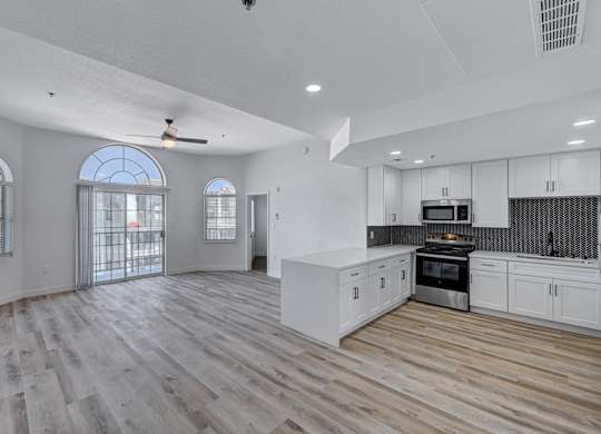 A spacious kitchen with wooden floors and white walls.