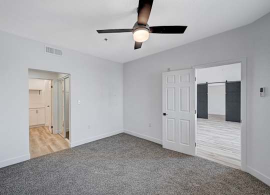 A room with a ceiling fan and carpeted floor.