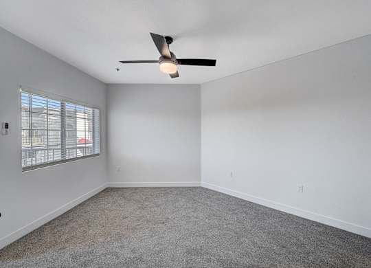 Empty room with a ceiling fan and carpeted floor.