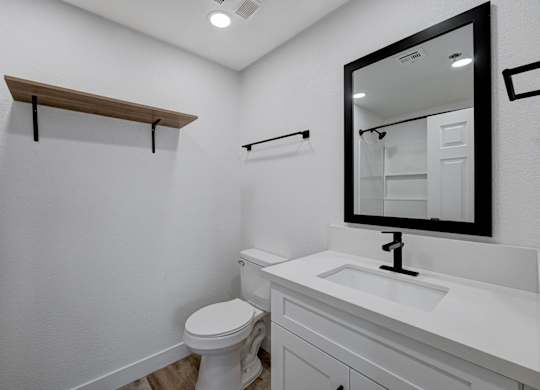 A white bathroom with a toilet, sink, and mirror.
