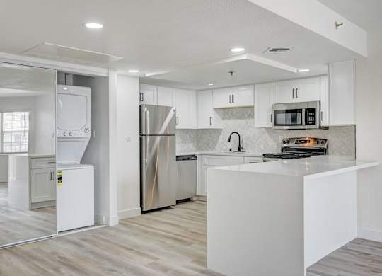 A modern kitchen with a white island and stainless steel appliances.