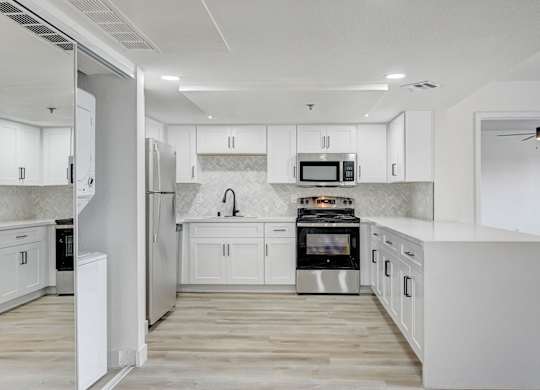 A modern kitchen with white cabinets and stainless steel appliances.