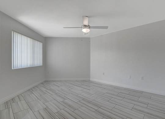 A room with a ceiling fan and a window with blinds.