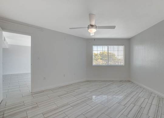 A room with a ceiling fan and a window with blinds.