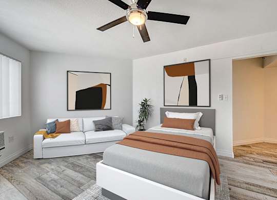 A bedroom with a bed, couch, and a ceiling fan.