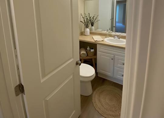 A white bathroom with a toilet, sink, and mirror.