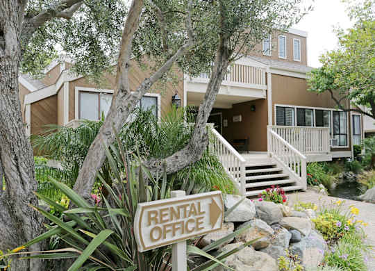 A rental office sign is in front of a two-story house.