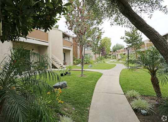 A pathway leads through a landscaped area with a building in the background.