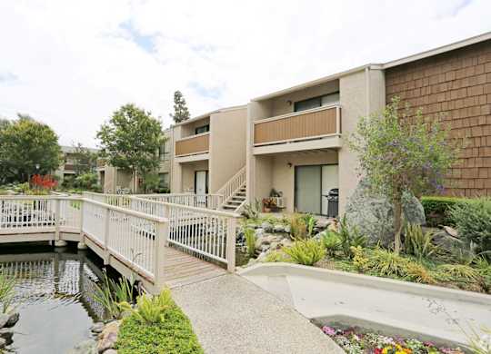 A bridge over a pond leads to a building.