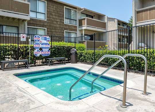 A small pool surrounded by a metal fence with a sign on it.