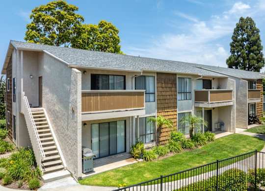 A modern two-story apartment building with a staircase leading to the entrance.