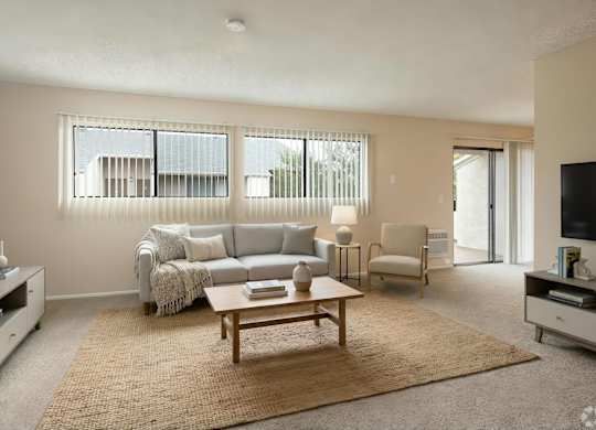 A living room with a grey couch, a coffee table, and a flat screen TV.