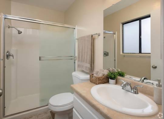 A bathroom with a toilet, sink, and shower.