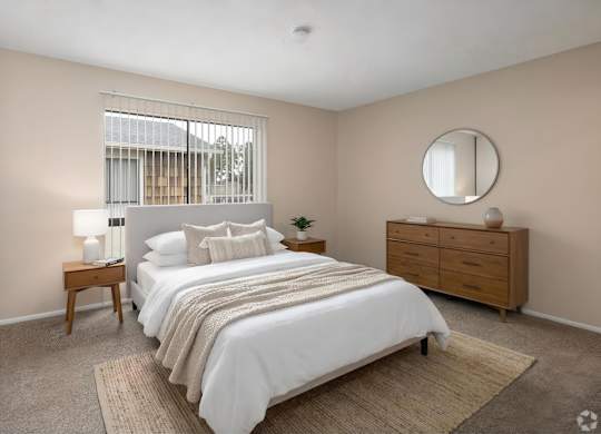 A bedroom with a large bed, a nightstand, and a window with blinds.