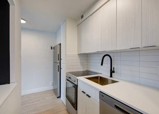 A kitchen with white cabinets and a black faucet.