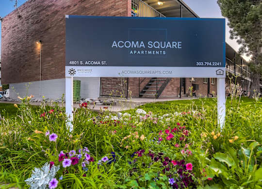 A sign for Acoma Square Apartments is in front of a building.