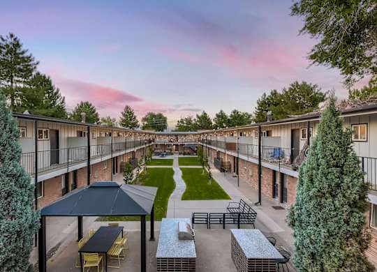 A sunset view of a courtyard with a picnic table and chairs.