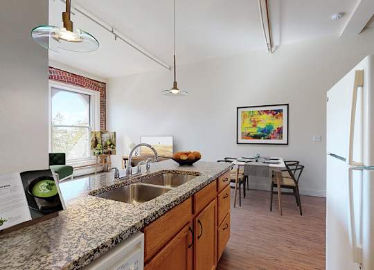 A kitchen with a refrigerator, sink, and a dining table with chairs.