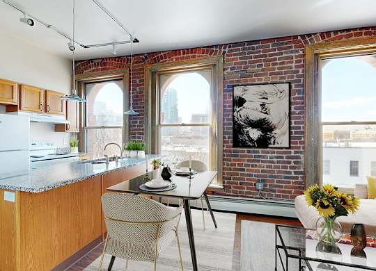 Open-plan kitchen with island,  dining table and living area with sofa. 3 large floor-to-ceiling windows look out on to the city landscape.