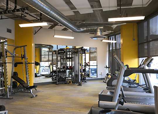 A gym with a variety of equipment including treadmills, weights, and exercise machines.