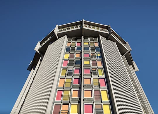 A tall building with a row of windows in red, yellow, orange, and pink.
