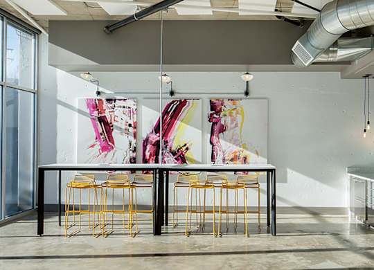 A room with a table and chairs and a painting on the wall.
