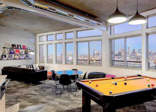 A room with a pool table and a view of the city.