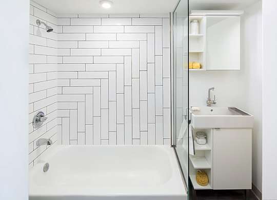 A white bathroom with a white tub and a white sink.
