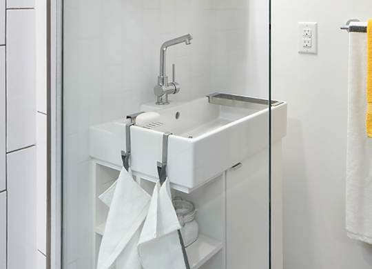 A white sink with a silver faucet and a white cabinet with a glass door.