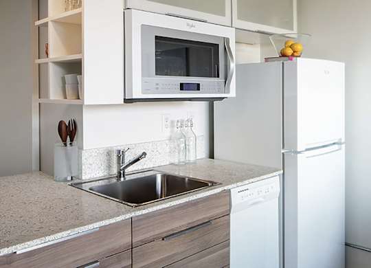 A modern kitchen with a white refrigerator, microwave, and dishwasher.