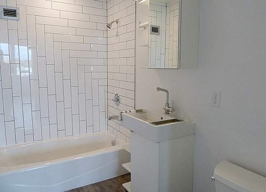 A white bathroom with a tub, sink and mirror.