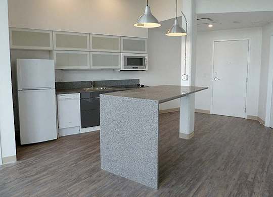 A kitchen with a white fridge and a grey island.