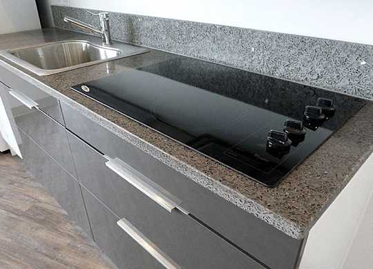 A kitchen counter with a sink and a black cutting board.