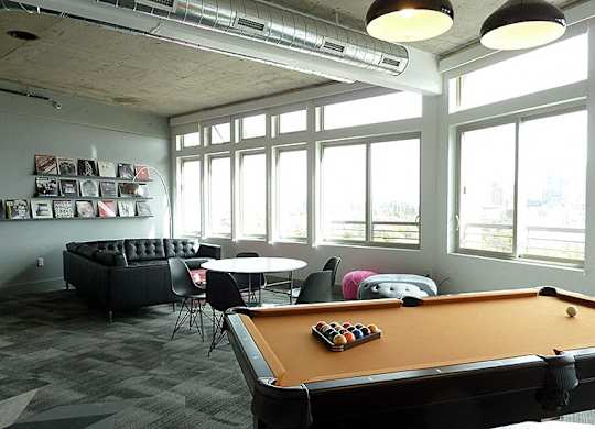 A pool table is in the middle of a room with a couch and chairs.