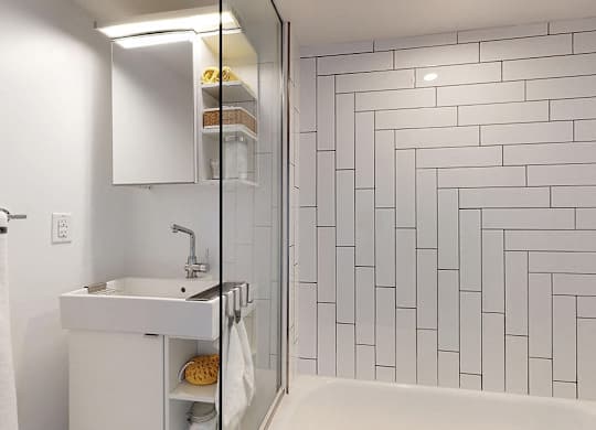 A white sink with a white cabinet and a white bathtub in a bathroom.