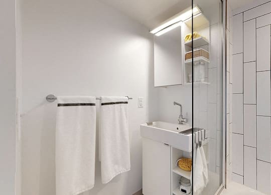 A white bathroom with a sink, mirror, and towel rack.