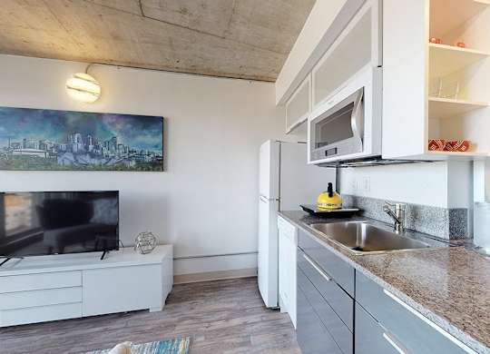 A modern kitchen with a white countertop and a television on the side.