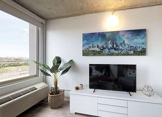 A room with a television, a plant, and a painting on the wall.