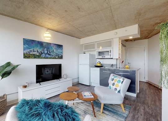 A living room with a blue rug and a painting on the wall.