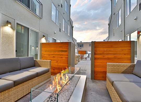 A modern patio with a fire pit and seating area.