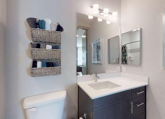 A bathroom with a white toilet, a sink with a cabinet and a mirror.