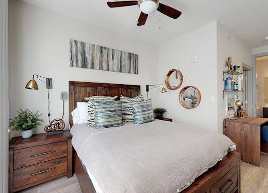 A bedroom with a bed, a chair, and a ceiling fan.