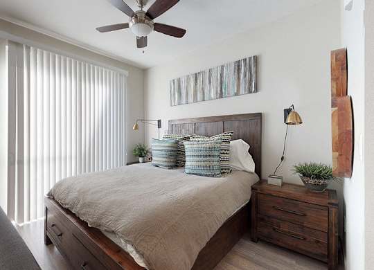 A bedroom with a bed, nightstand, and a ceiling fan.