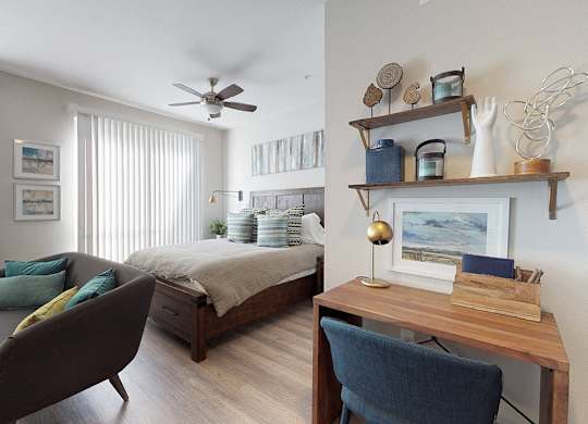A bedroom with a bed, a chair, and a desk.
